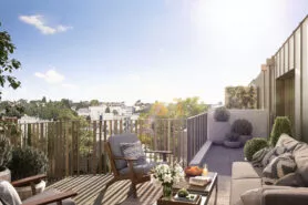 Une terrasse d'un immeuble en plein soleil où est présenté un salon de jardin.